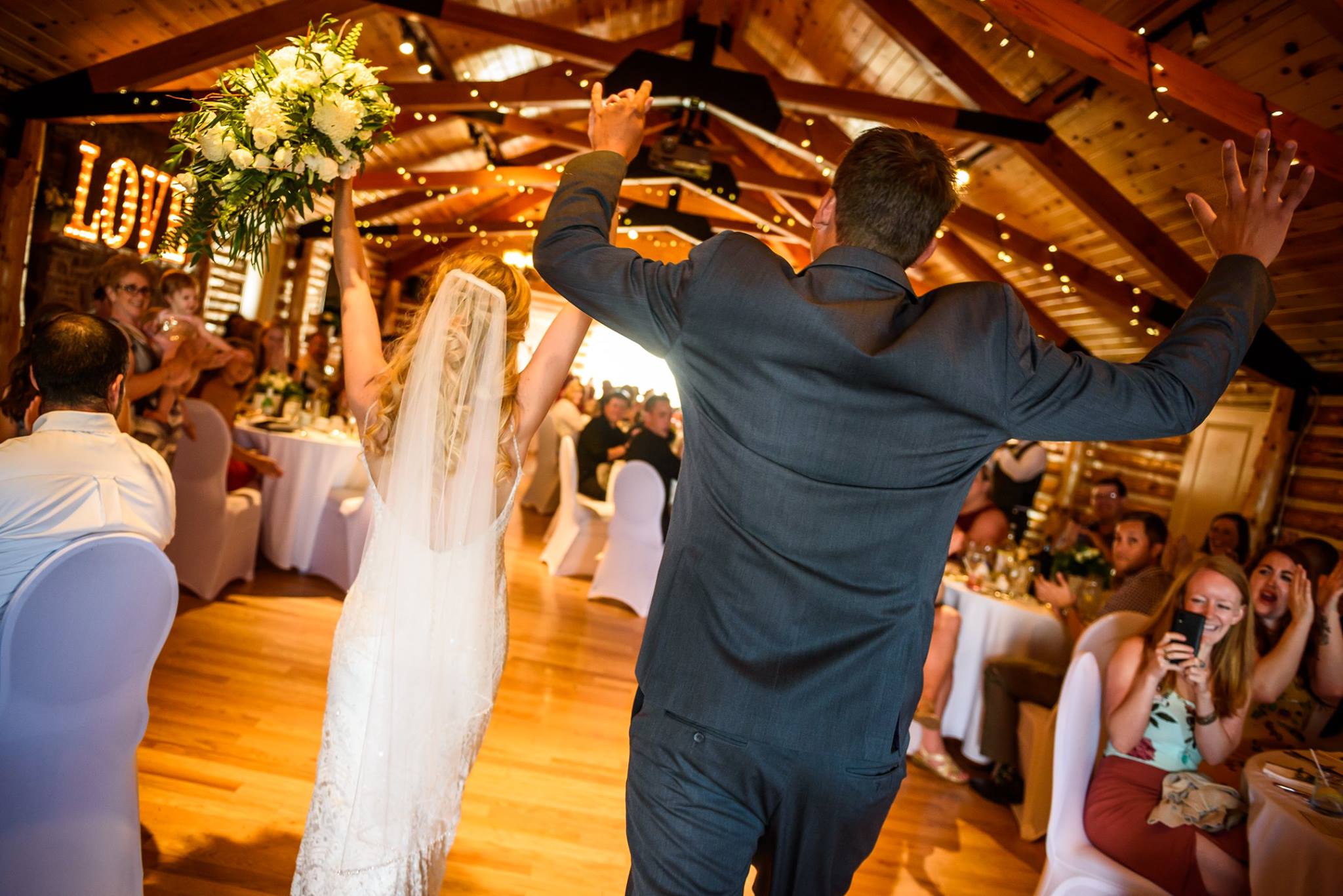 Bride and groom entering a lively rustic wedding reception