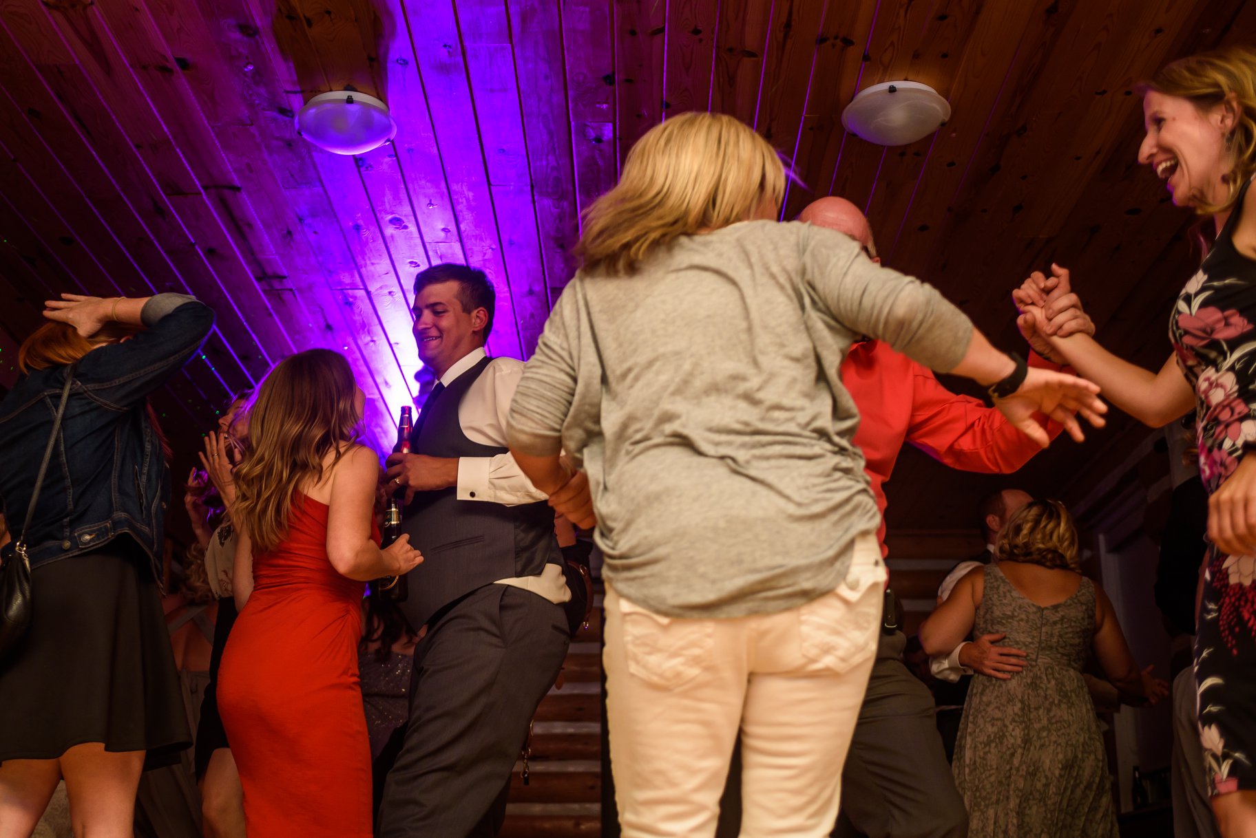 Wedding guests dancing under purple uplighting