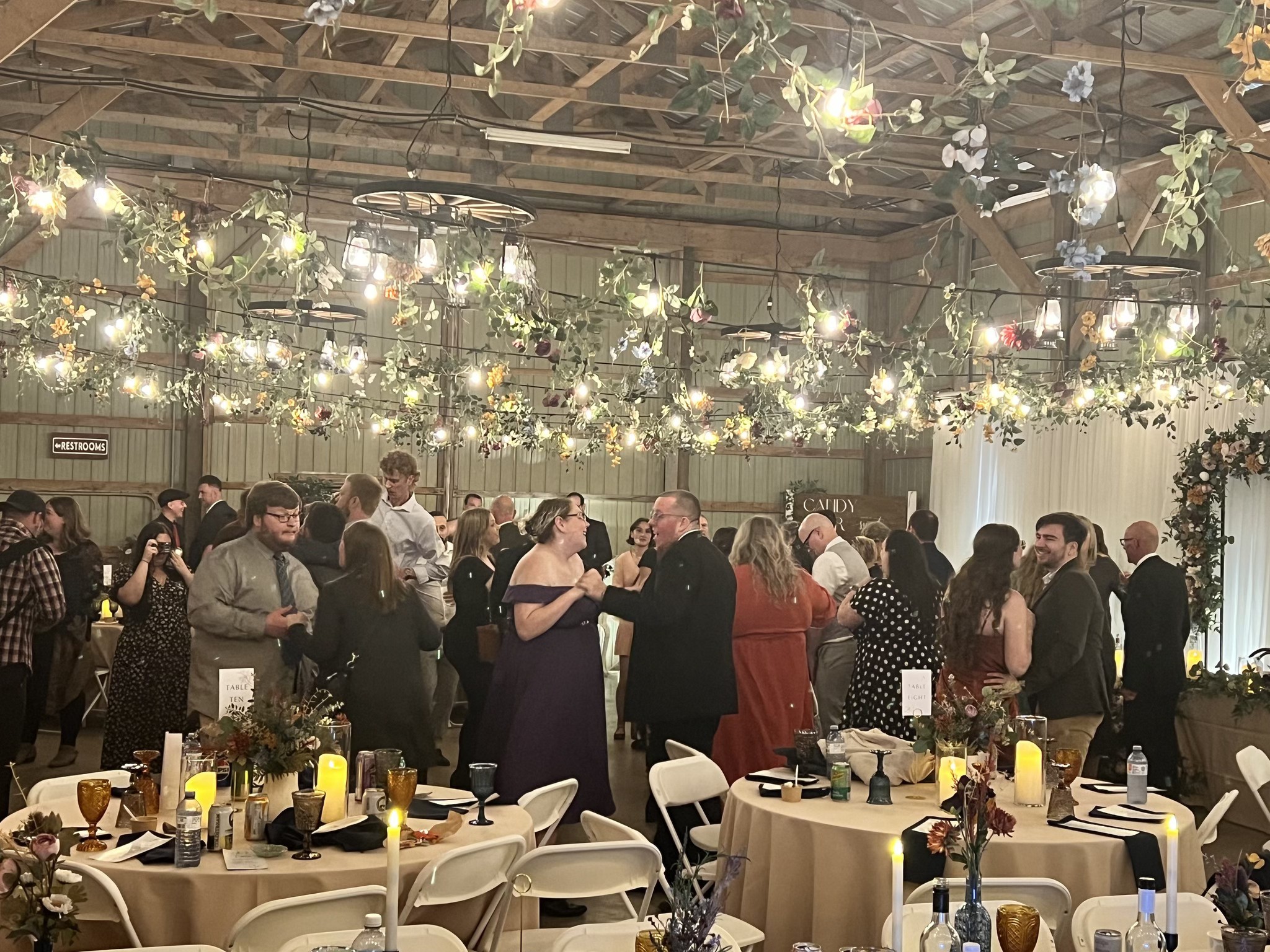 Wedding reception guests dancing under floral lighting