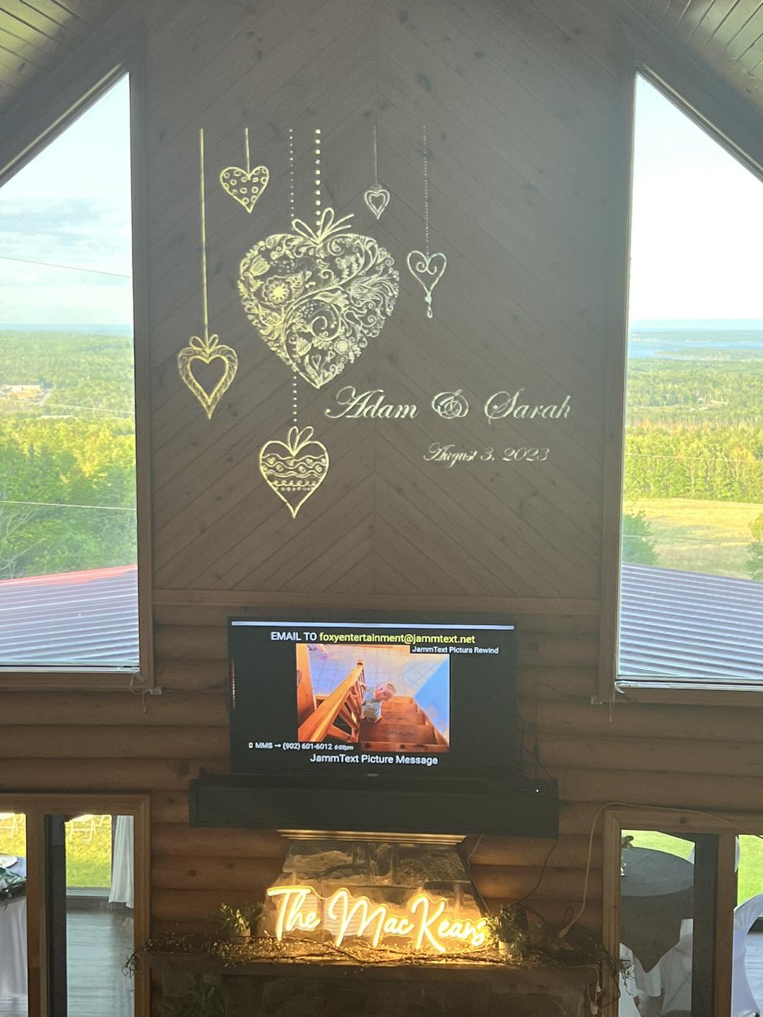 Heart-themed wedding monogram projection above a reception screen
